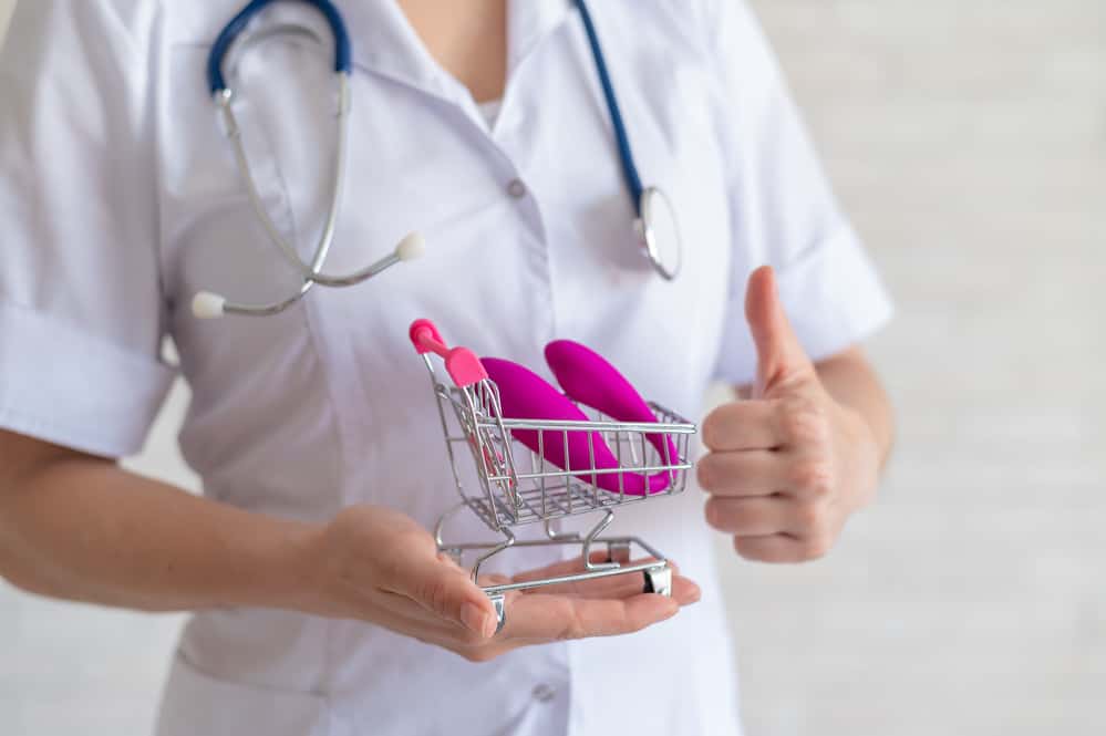 woman in medical uniform holding vibrator giving thumbs up