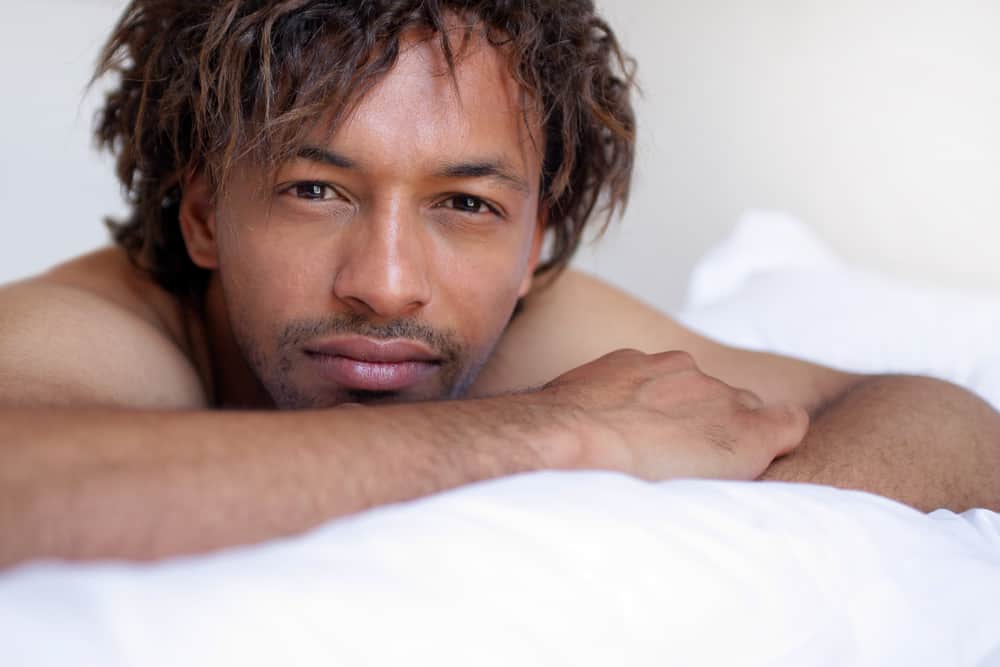black young man lying in white bed