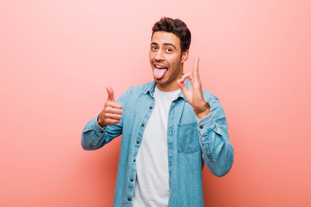 man sticking out tongue and giving thumbs up