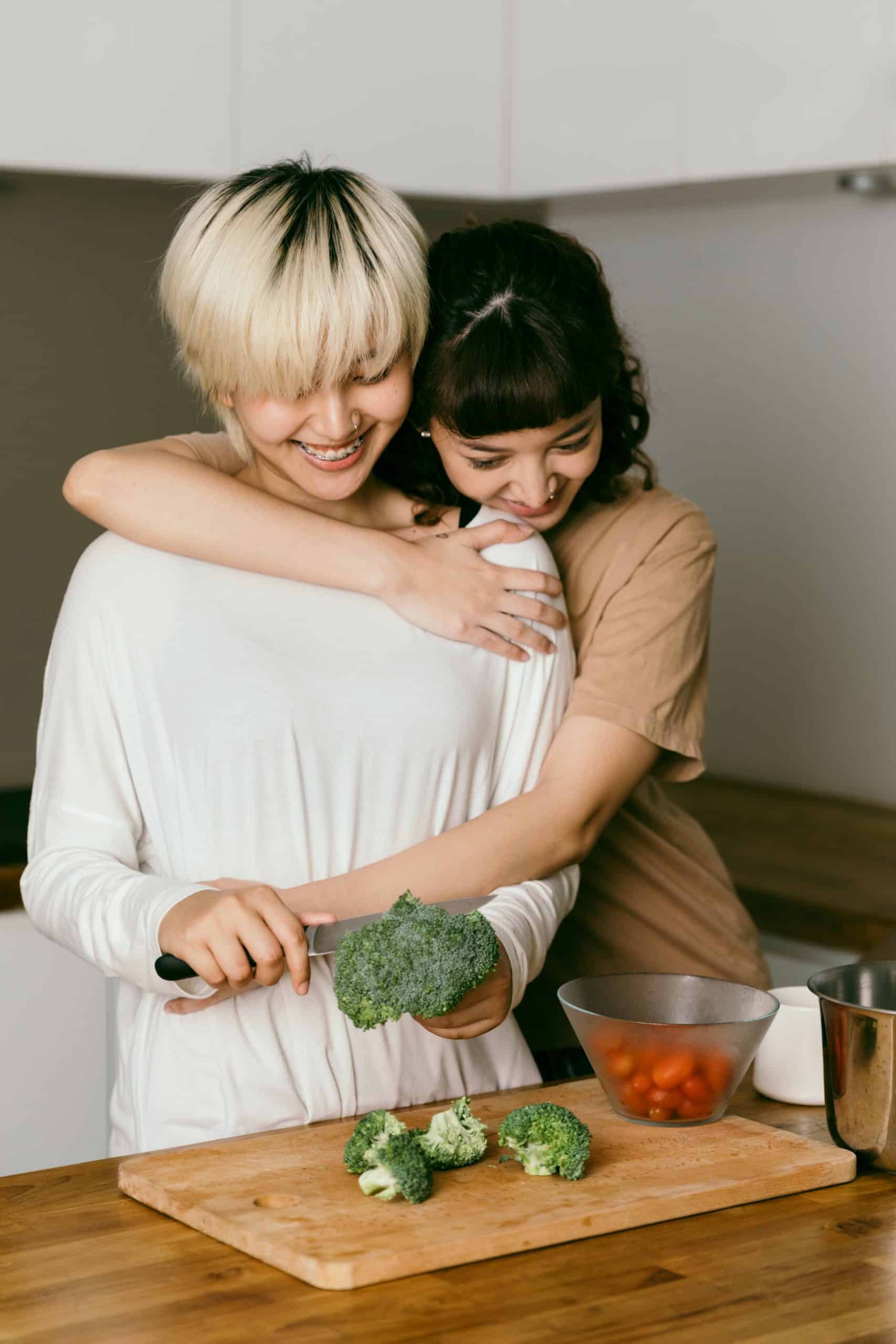 Woman being hugged while cutting vegetables