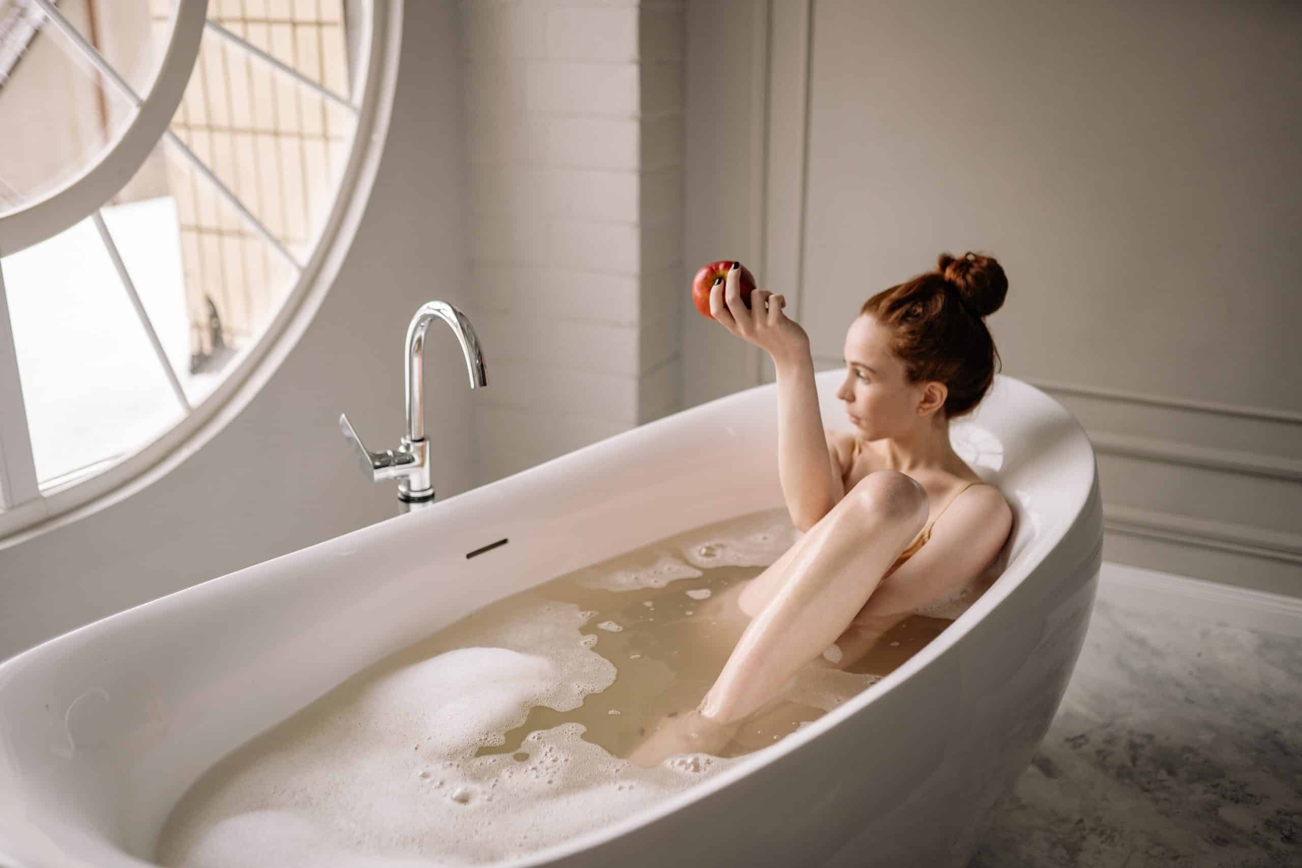woman holding an apple in a bath tub