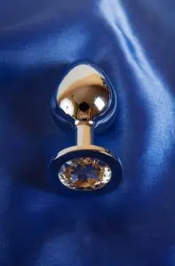 Metal sex toy butt plug on blue satin background
