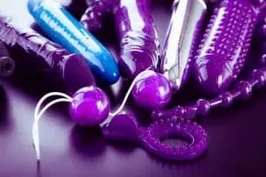 a collection of different types of sextoys, including dildo, vibrators and butt plugs over a dark wooden surface